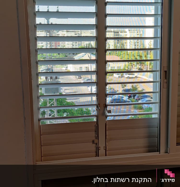 חלון עם תריסי אלומיניום פתוחים למחצה